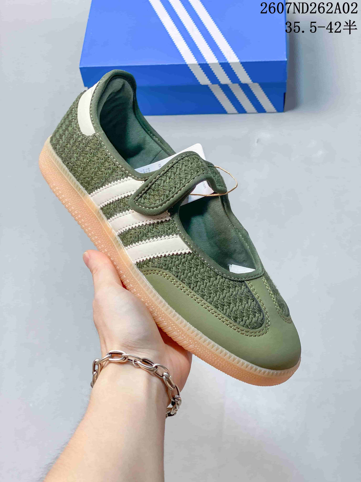 Angled side view of the olive-green sneaker with white stripes and hook-and-loop strap