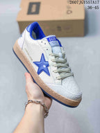 Close-up of a white Golden Goose Ball Star sneaker with a bright blue star, blue collar lining, and cream laces.