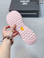 Underside of the pink shoe showing a repeating lug pattern and a yellow Vibram-branded insert.
