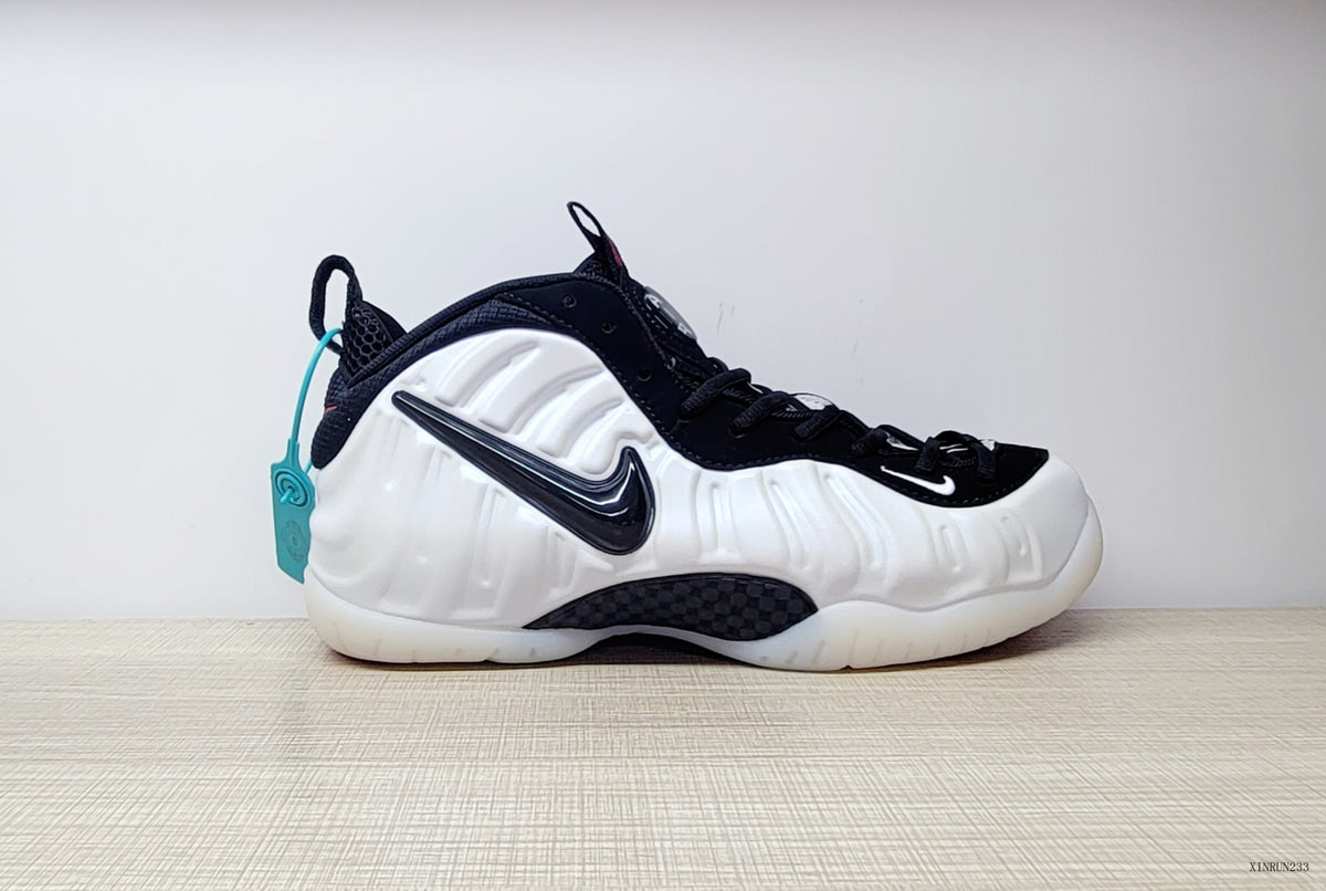 Side view of a white Nike Air Foamposite One sneaker with black Swoosh and dark accents