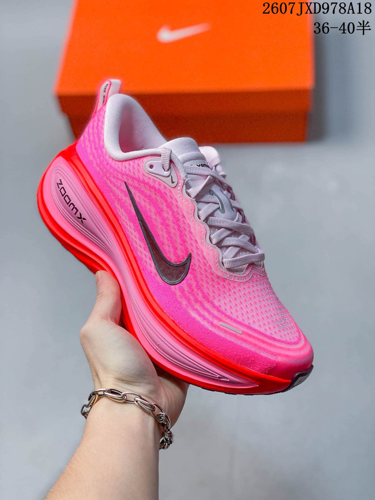 Angled side view of the pink and red sneaker showing the lace-up upper, Nike Swoosh and ZoomX branding.