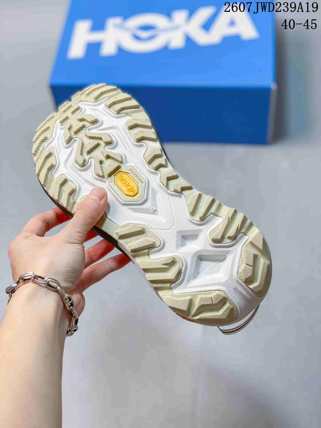 Underside view of the shoe showing the cream-and-white textured outsole and central yellow insert.