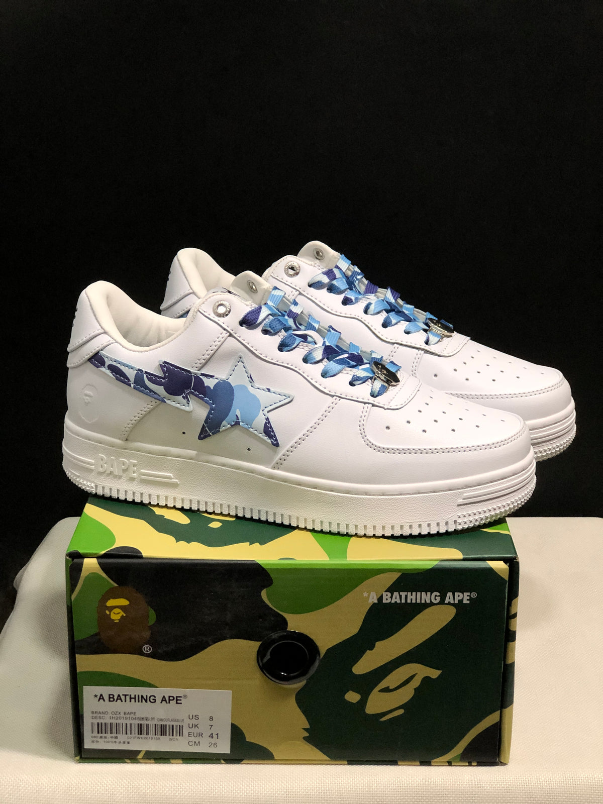 White and blue camouflage BAPE STA sneakers displayed above a camouflage shoe box; the box label shows US 8, UK 7, EUR 41, and CM 26.