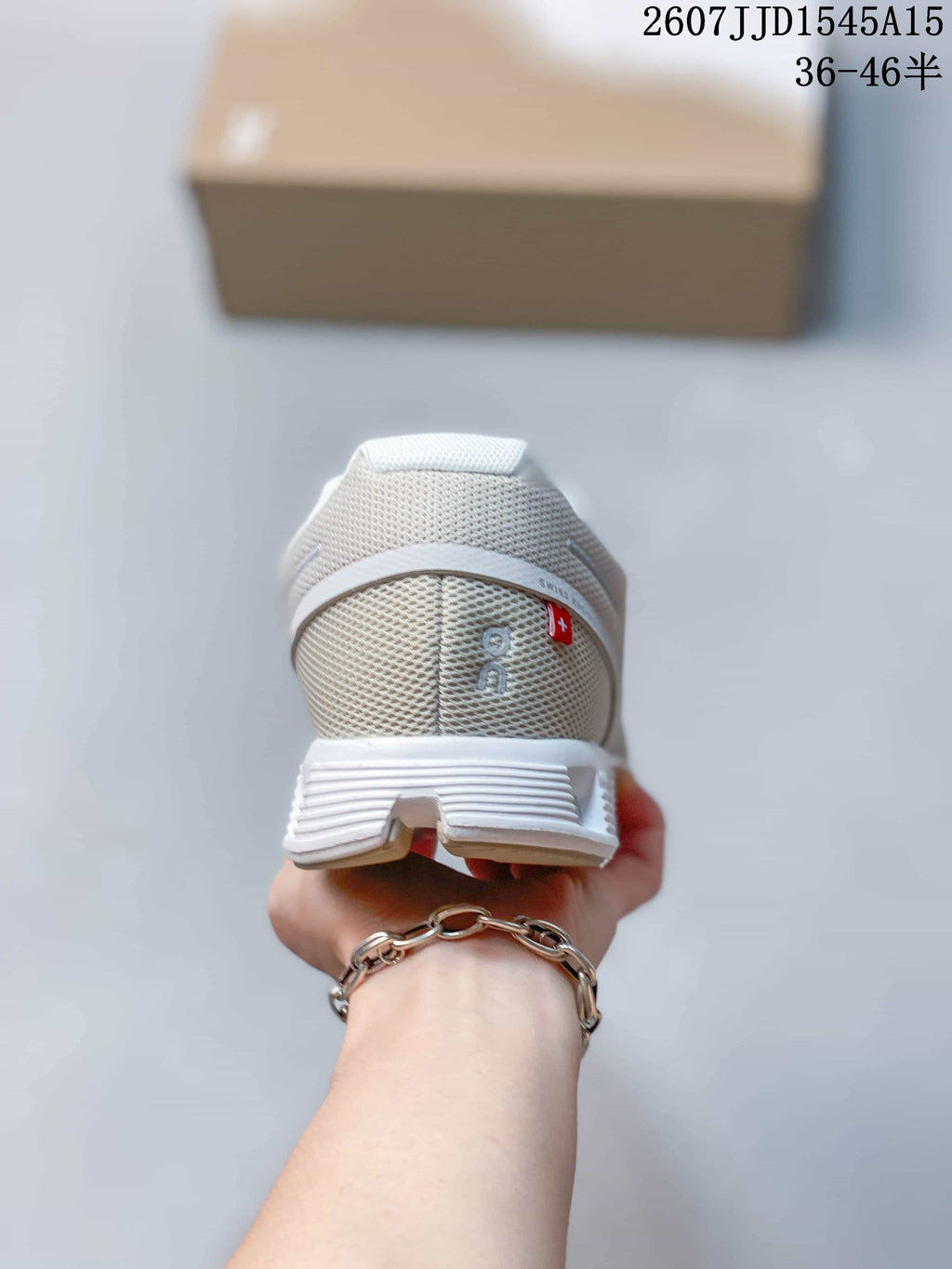 Rear view of a white and light gray sneaker showing the mesh heel, heel branding, and segmented outsole.