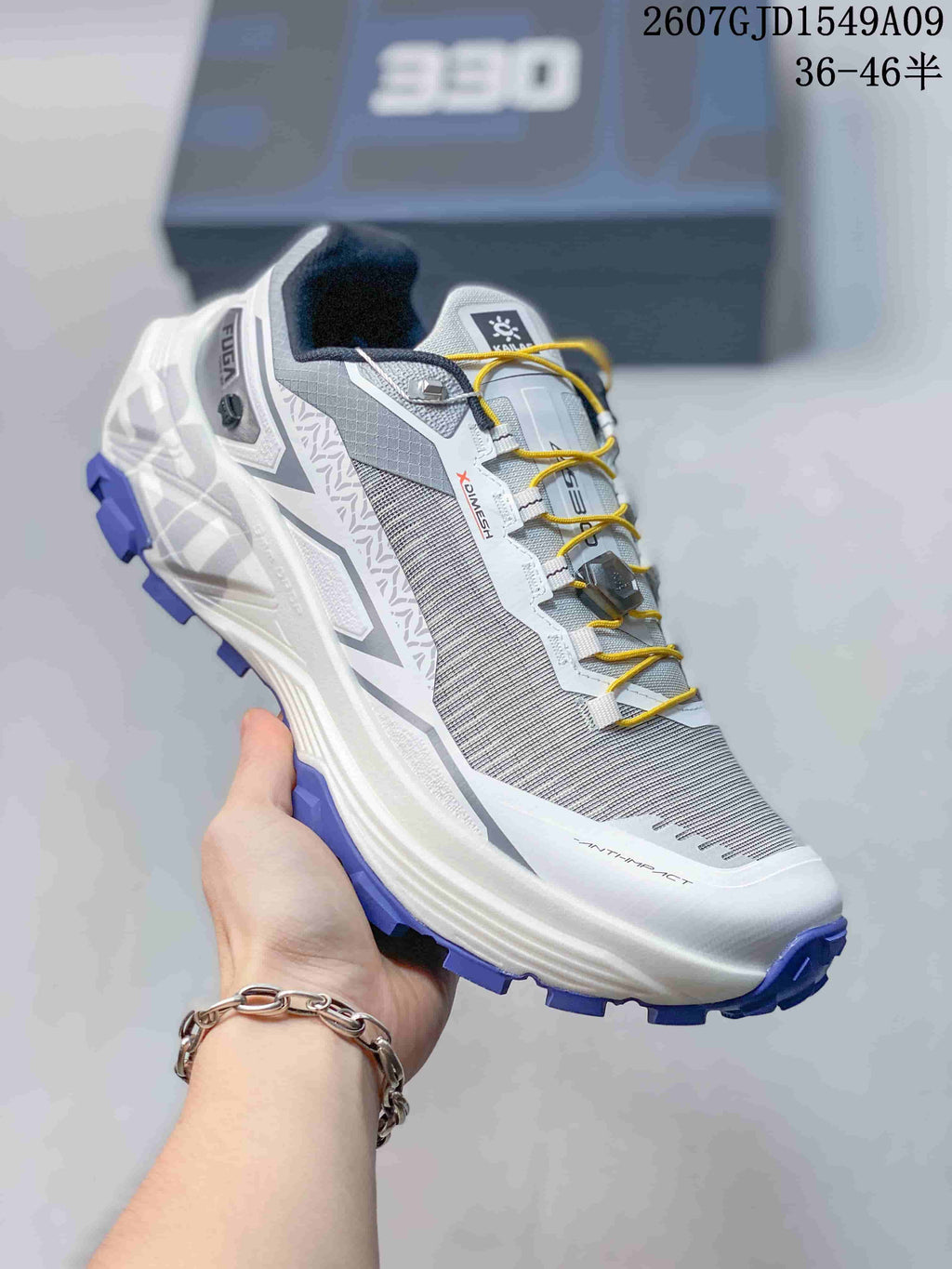 Angled side view of the Kailas Fuga Ex 330 shoe showing its grey upper, white midsole, yellow laces, and purple tread.