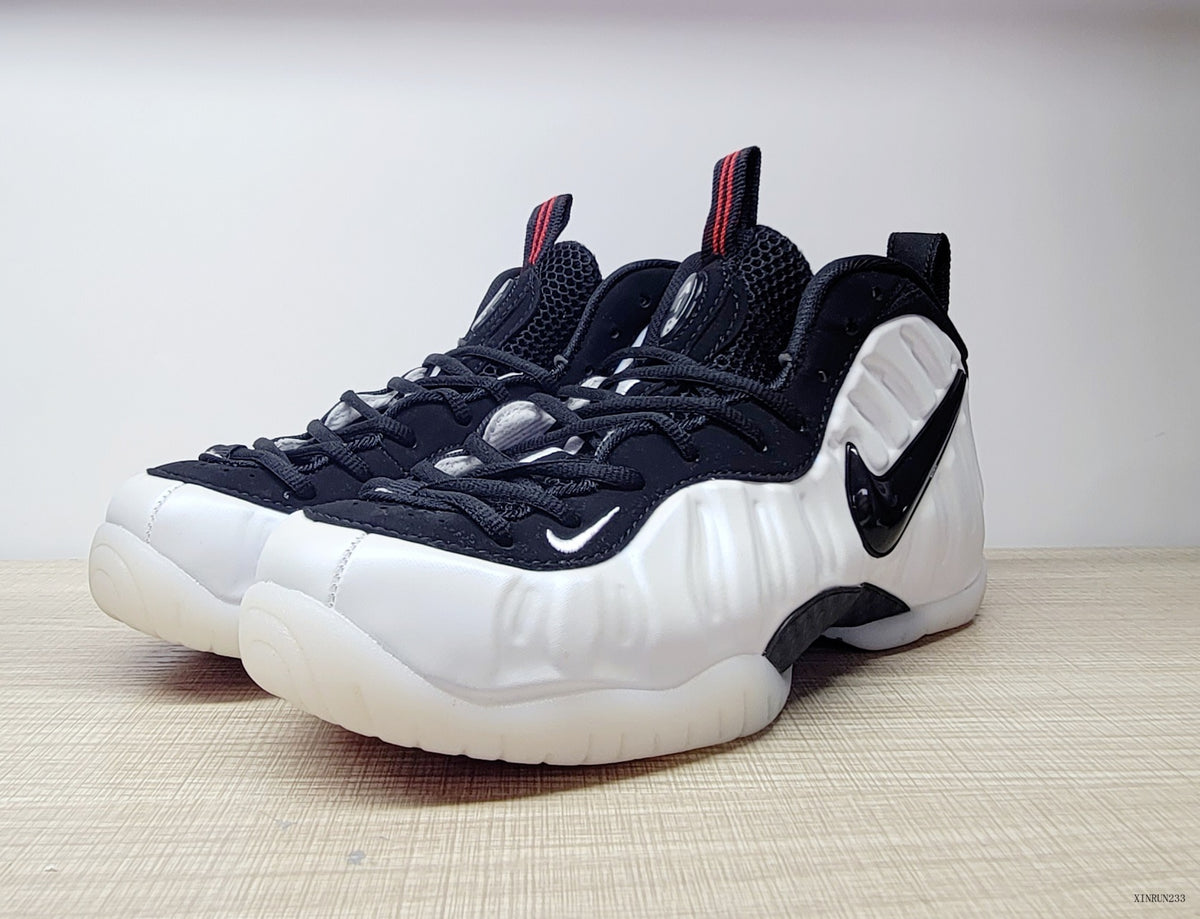 Pair of white Nike Air Foamposite One high-top sneakers with black laces and Swoosh details