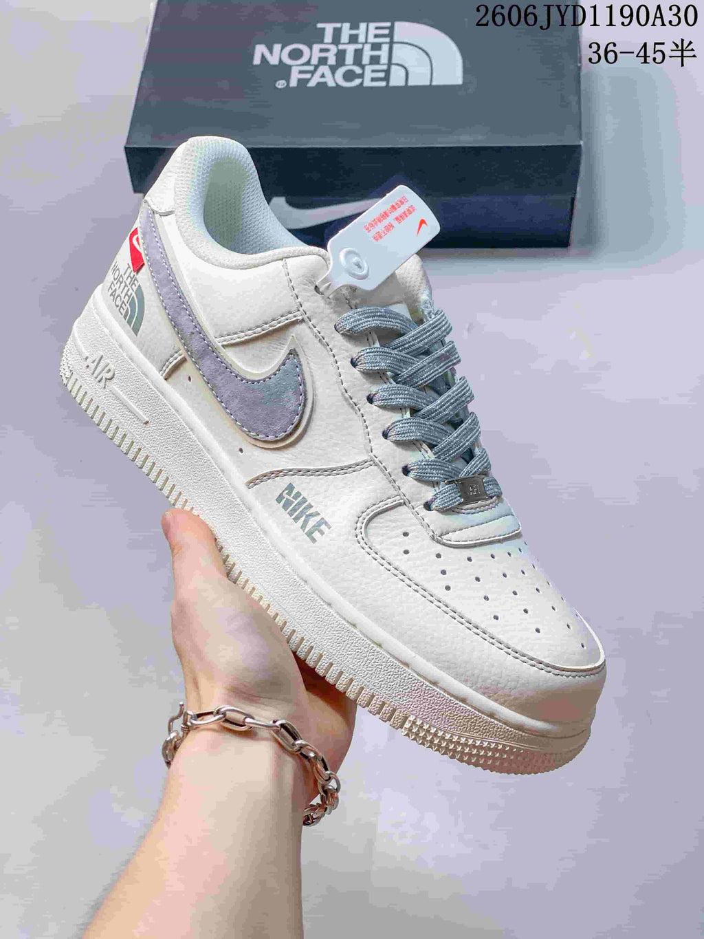 Close view of a cream low-top sneaker with gray Swoosh and patterned laces.