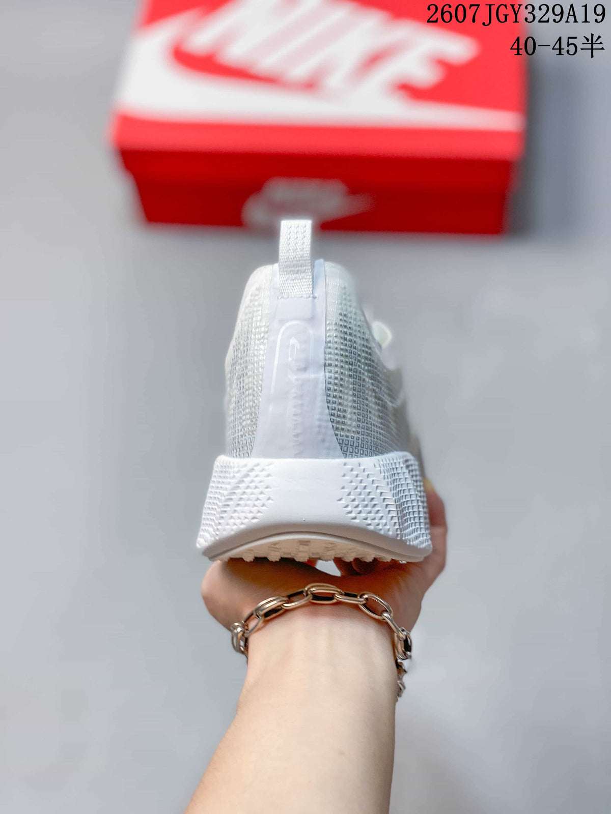 Rear view of the white sneaker showing the heel pull tab, padded collar, and textured heel section.