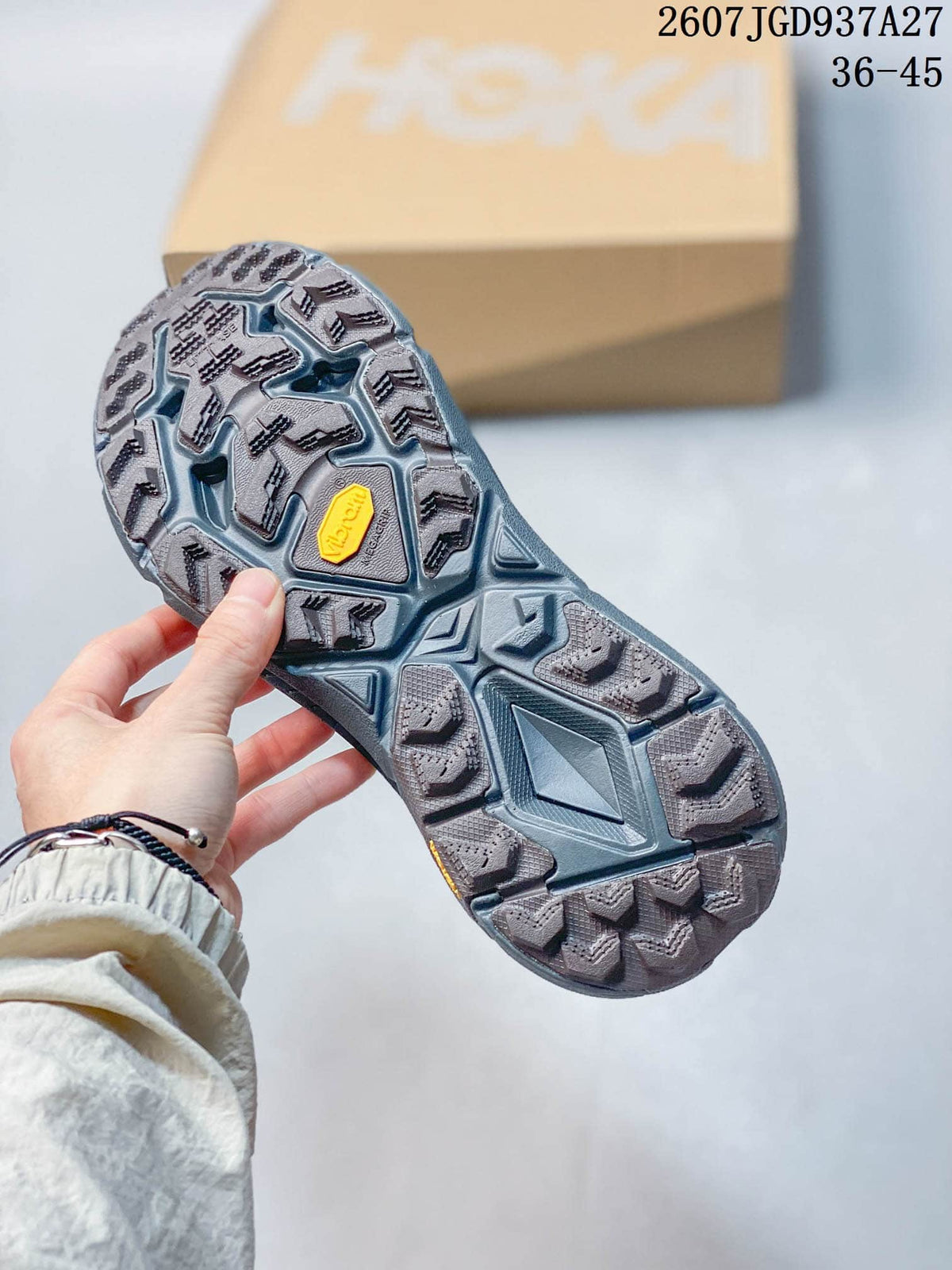 Close view of the sneaker outsole showing a gray lugged tread pattern and yellow sole branding.