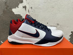 Side view showing the navy Swoosh, white panels, and red heel of a Nike Kobe basketball shoe