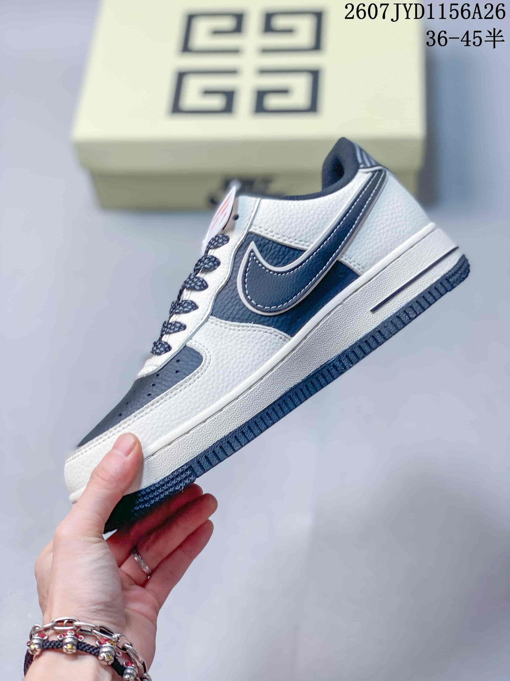Side profile of the white and navy low-top sneaker showing the layered side logo graphic and white midsole.