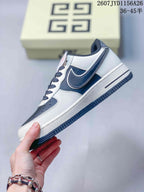 Side profile of the white and navy low-top sneaker showing the layered side logo graphic and white midsole.