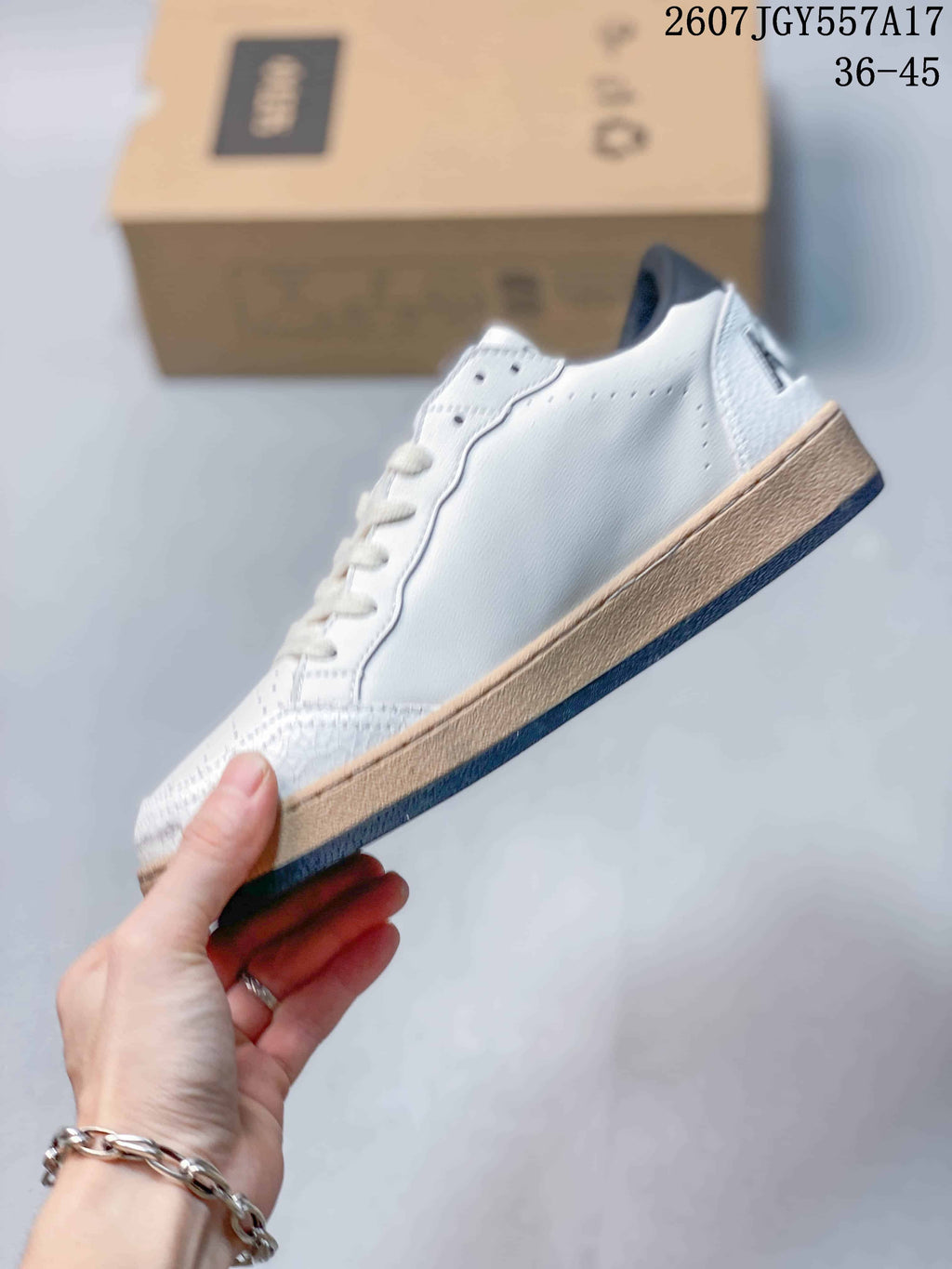 Side view of the white low-top sneaker showing the clean lateral panel, lace area, gum-colored midsole, and dark outsole.