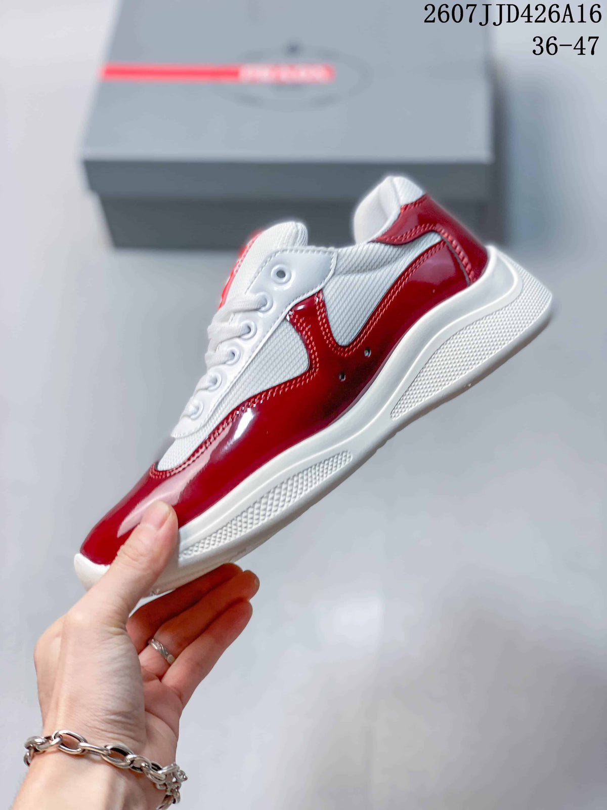 Side view of a red and white low-top sneaker showing glossy red panels, white sections, lace fastening, and a raised sole.
