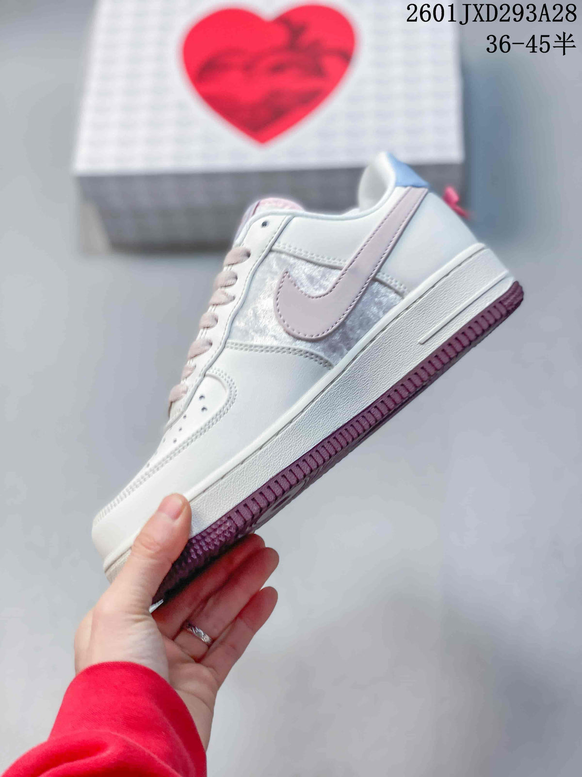 Side view showing the white low-top sneaker, pale pink Swoosh, textured side panel, and burgundy outsole.
