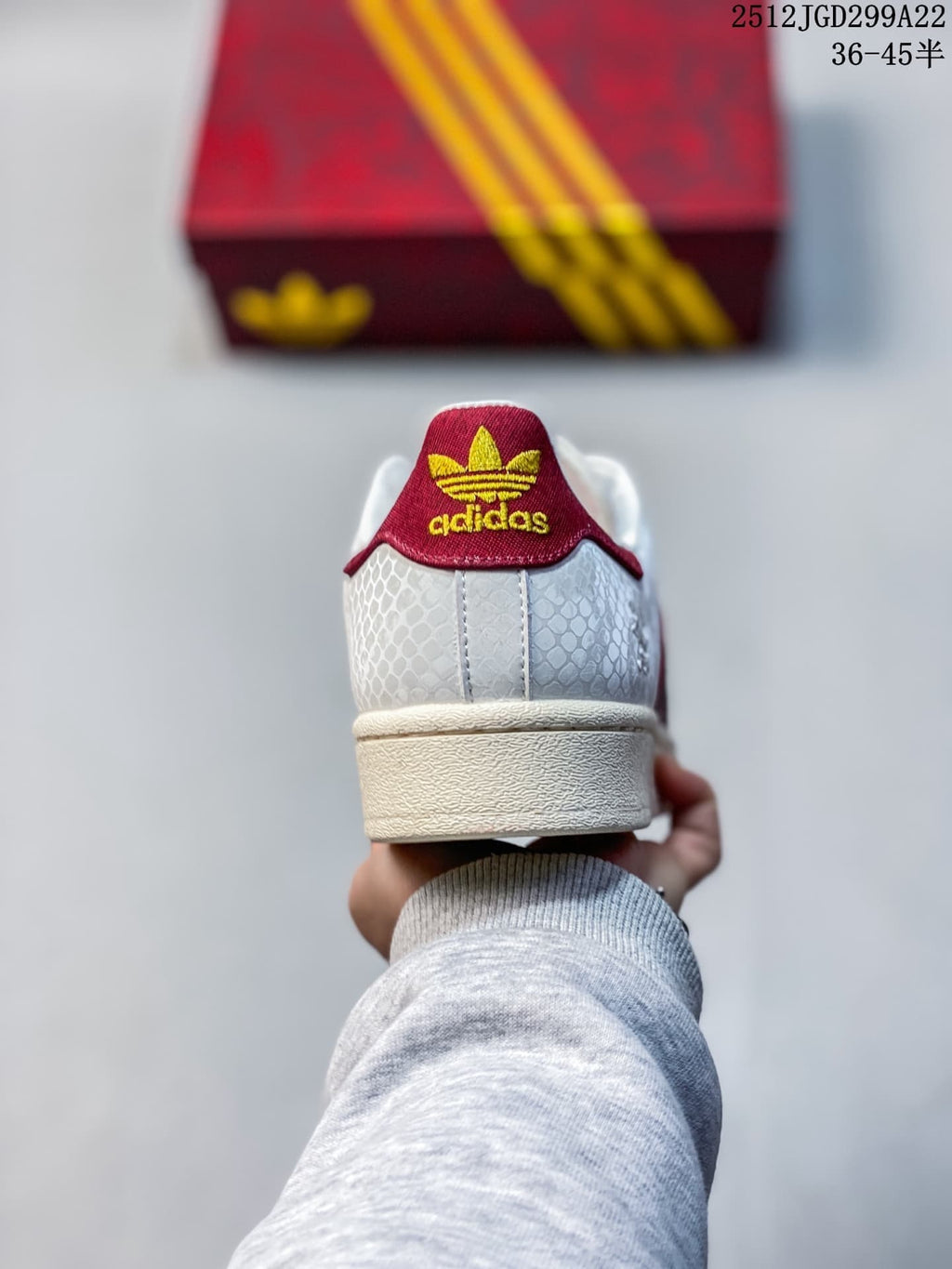 Rear view showing the textured white heel, red heel tab, and gold-colored adidas branding.