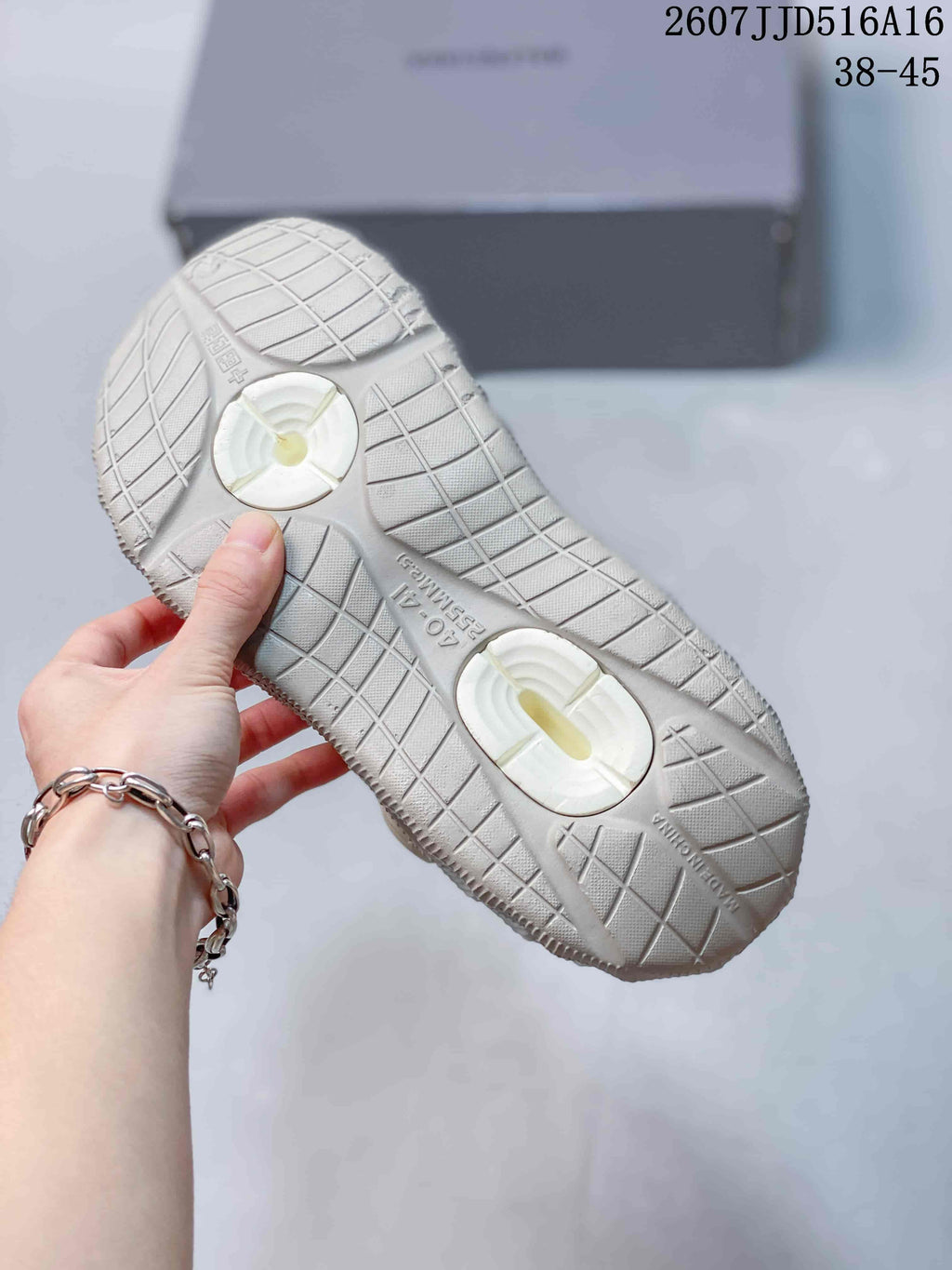 Underside of a clog showing a textured outsole with geometric tread and two circular recessed areas.