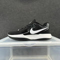 Side view of a black low-top Nike sneaker with a white side logo and white midsole.