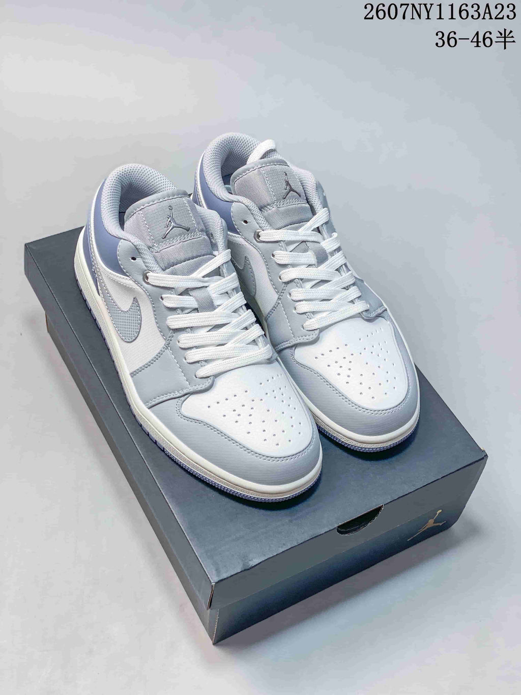 Pair of light grey and white Jordan low-top sneakers displayed on a Jordan shoebox.