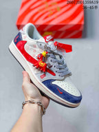 White, red, and navy low-top sneaker with patterned panels, mixed laces, and a decorative hanging charm.