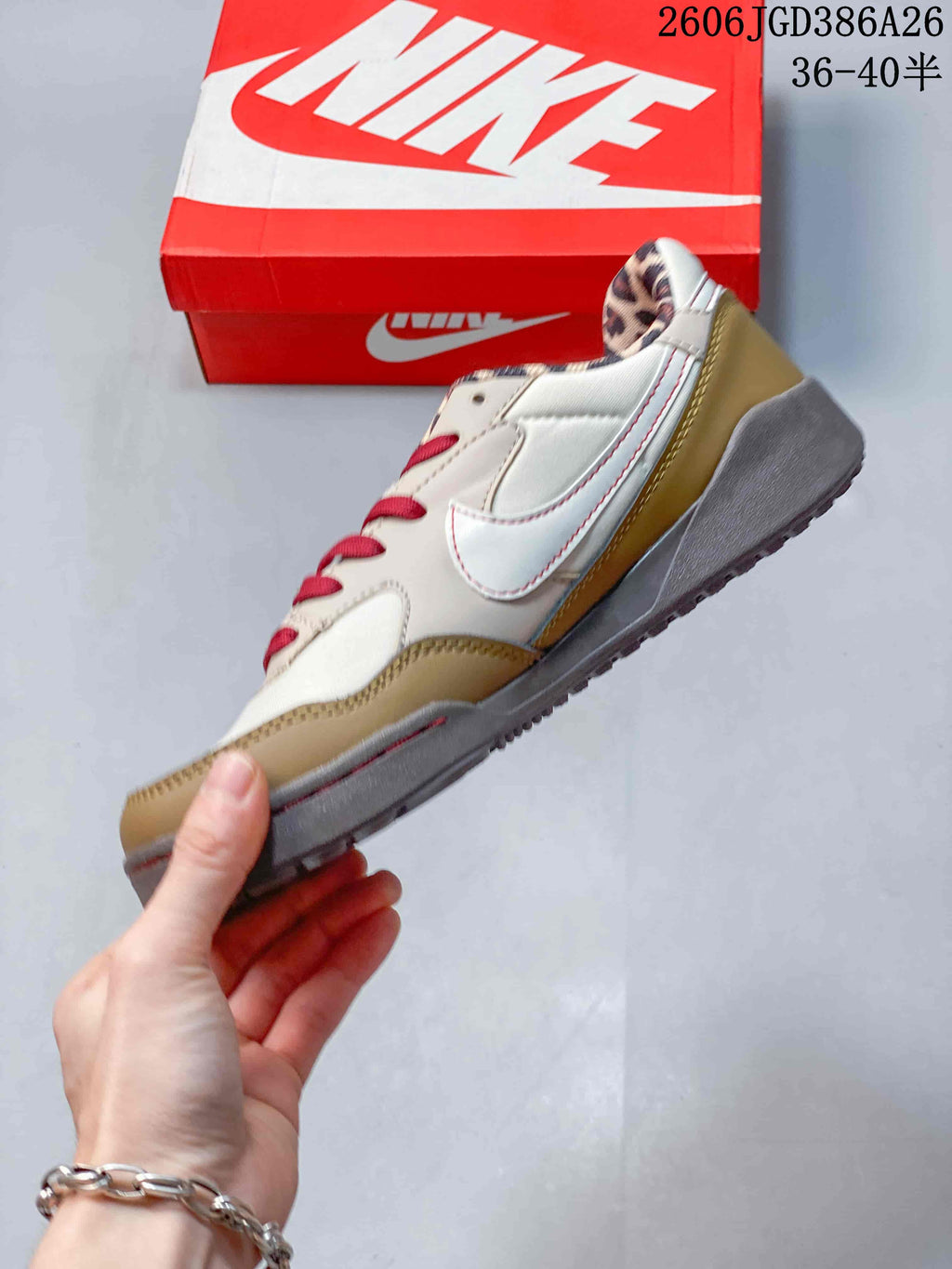Side profile showing the cream and tan upper, red stitching details, gray midsole and textured outsole.