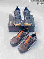 Two visible Adidas Terrex colorways arranged together, including dark gray with gum accents and brown with orange details.