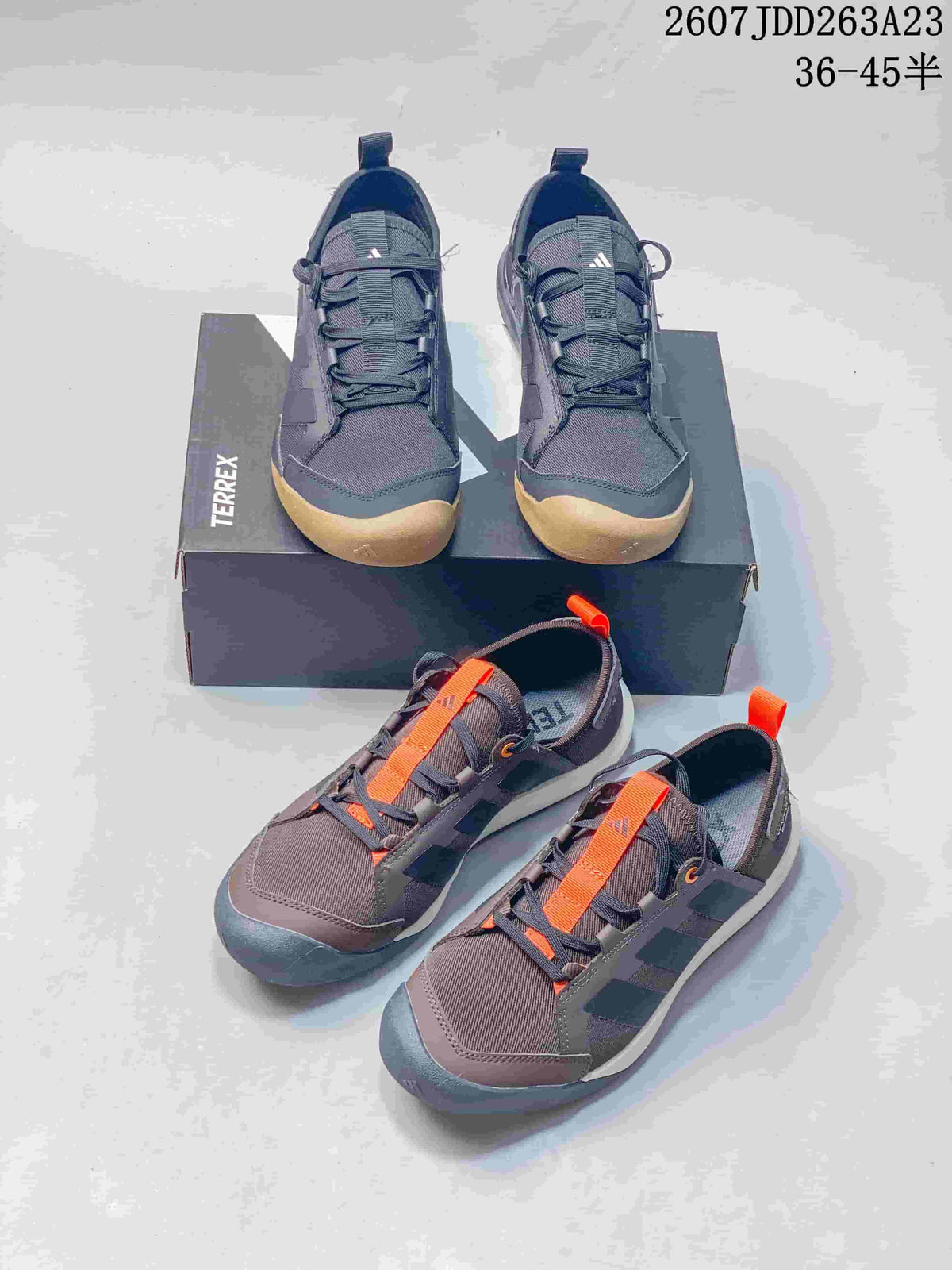 Two visible Adidas Terrex colorways arranged together, including dark gray with gum accents and brown with orange details.