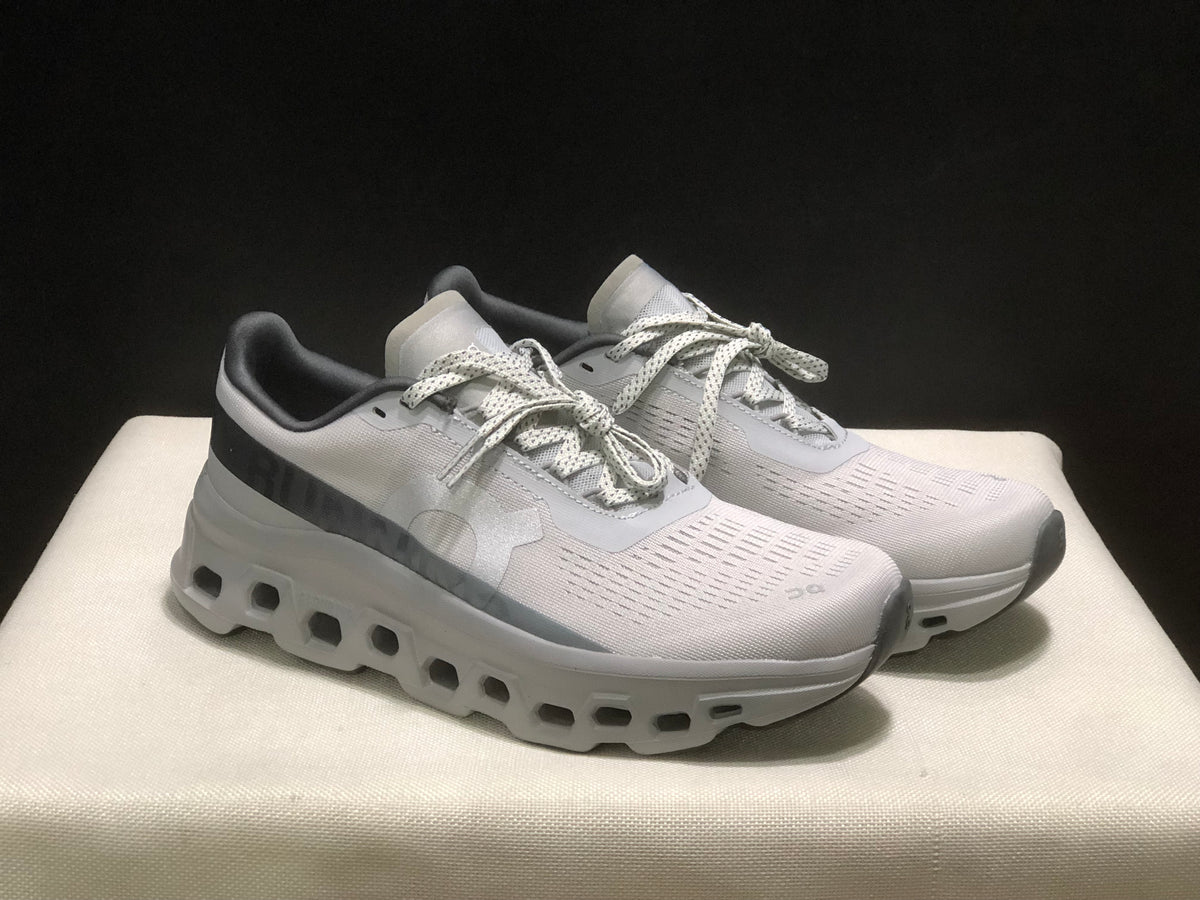 Three-quarter view of the light gray and white sneaker pair highlighting the lace-up design and thick white outsoles.