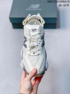 Front view of a white New Balance 9060 sneaker showing the mesh toe area, layered overlays, laces and 9060 tongue marking.