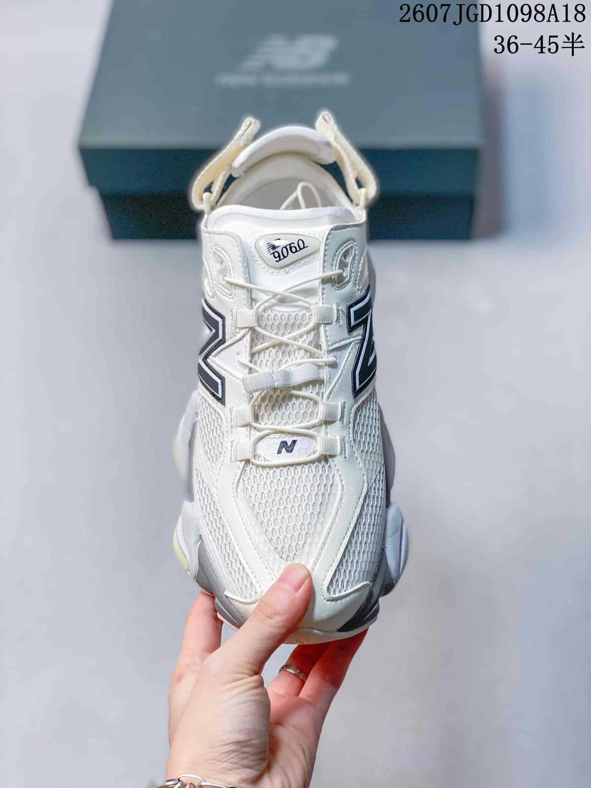Front view of a white New Balance 9060 sneaker showing the mesh toe area, layered overlays, laces and 9060 tongue marking.