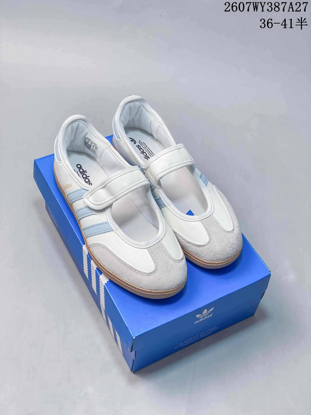 White adidas Samba Jane sneakers with light blue stripes and adjustable straps displayed on a blue shoe box.