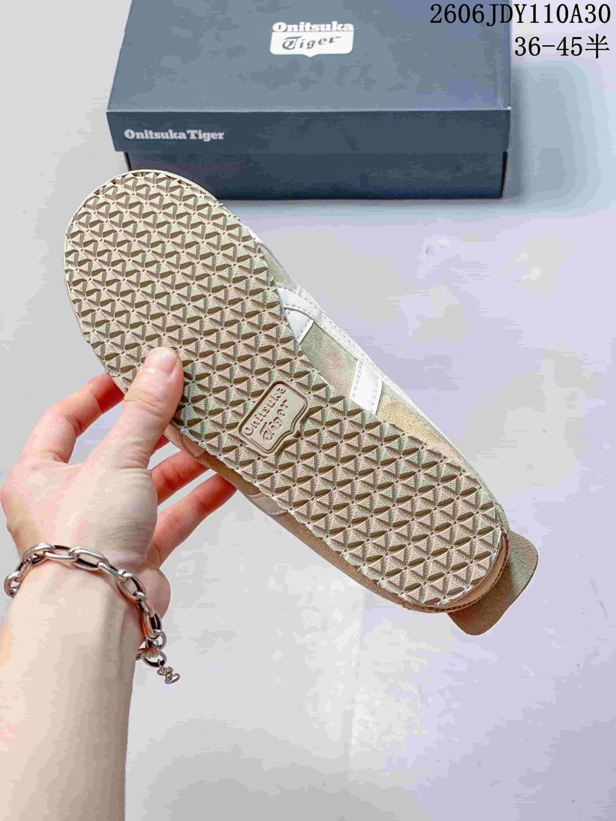 Close-up of the textured outsole and shoebox of beige Onitsuka Tiger sneakers