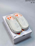 Pair of white Nike Mind slip-on clogs displayed on a Nike Mind box, showing the perforated upper, enclosed toe, open heel, and orange outsole pods.