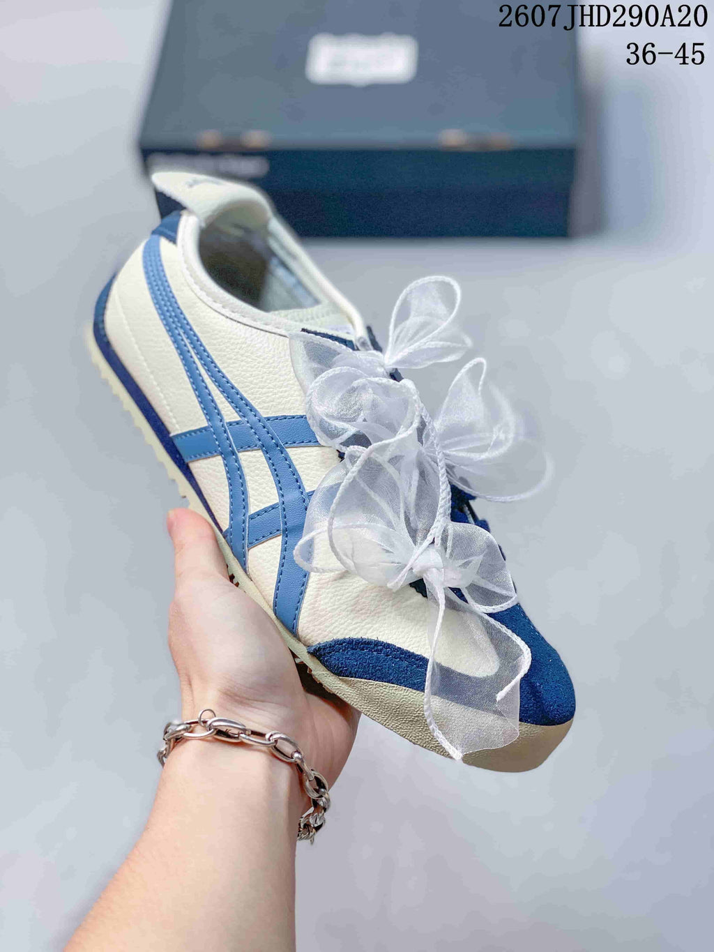 Side view of a white sneaker with blue stripes, blue toe detailing, and translucent ribbon laces.