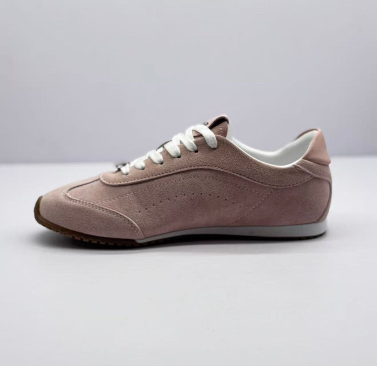 Opposite side view showing the pink sneaker's stitched panels and low-profile shape.
