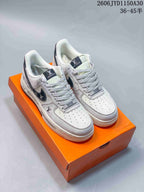 Pair of white and gray low-top sneakers with dark side accents and patterned laces on an orange box