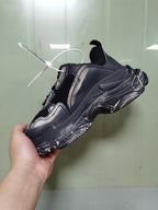 Rear-side view of the black and grey sneaker showing the layered upper, heel construction, textured sole, and pull tab.