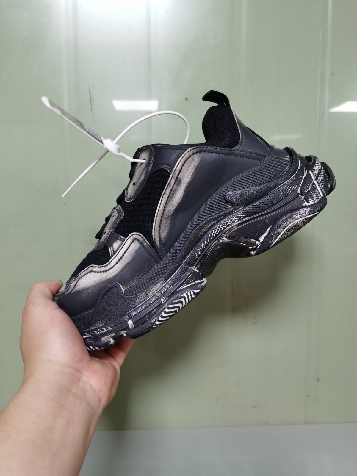 Rear-side view of the black and grey sneaker showing the layered upper, heel construction, textured sole, and pull tab.