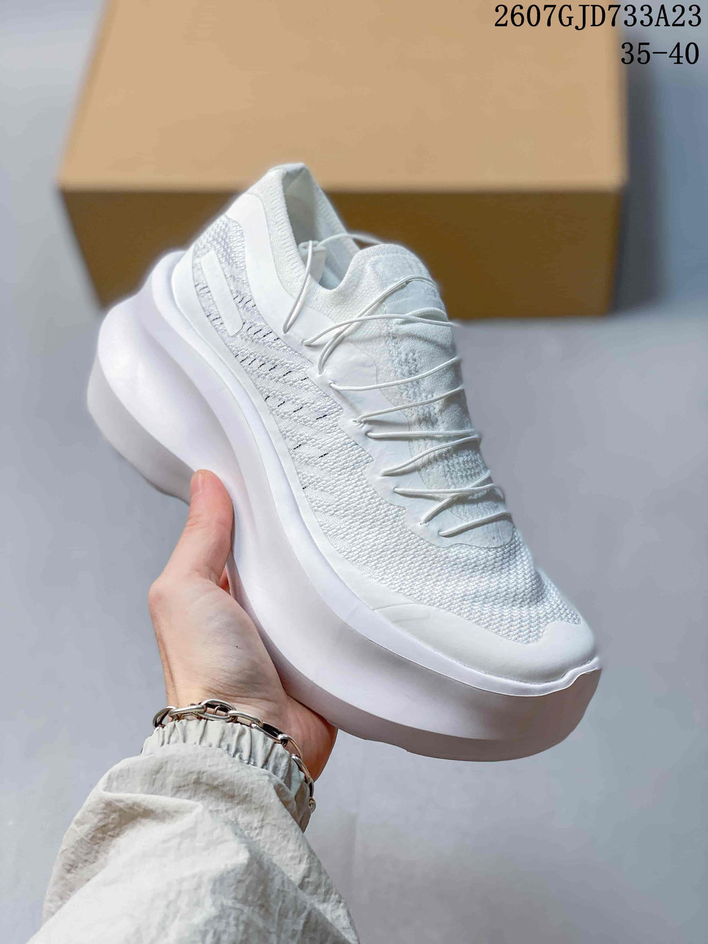 Angled view of the white sneaker highlighting the side detailing, laces and thick sole.