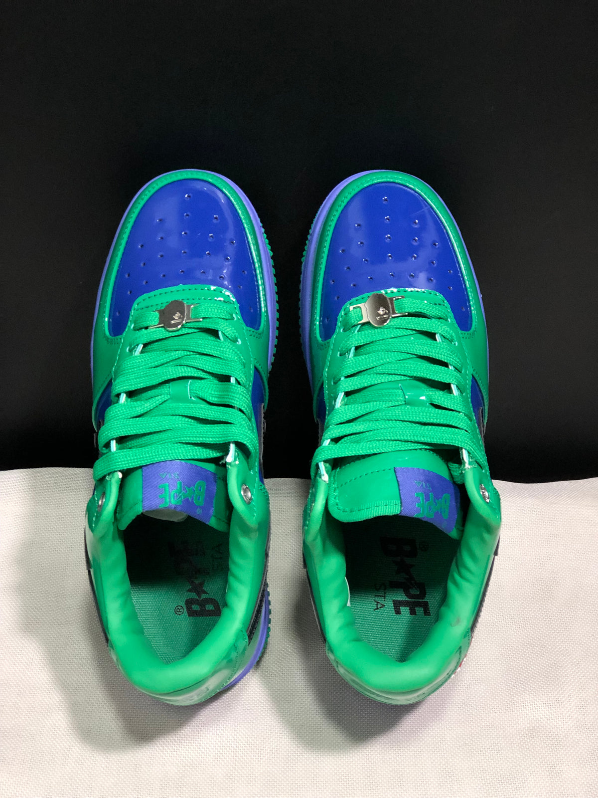 Top-down view showing green laces, blue perforated toe panels and padded green collars.