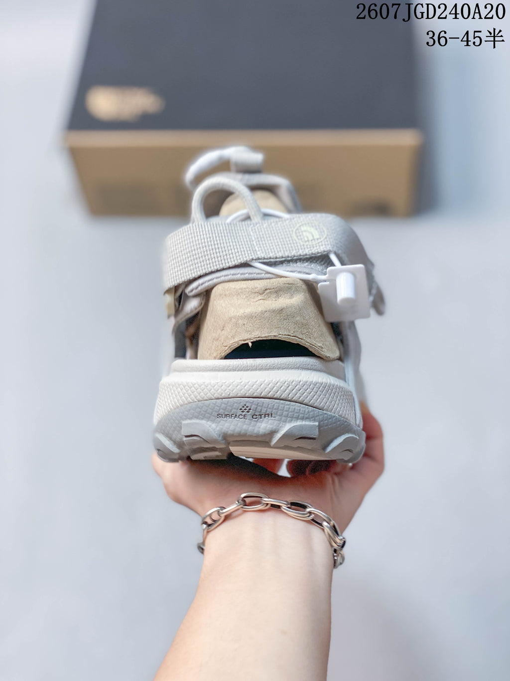 Rear view of a sandal showing the heel area, toggle fastening cord, and textured outsole.