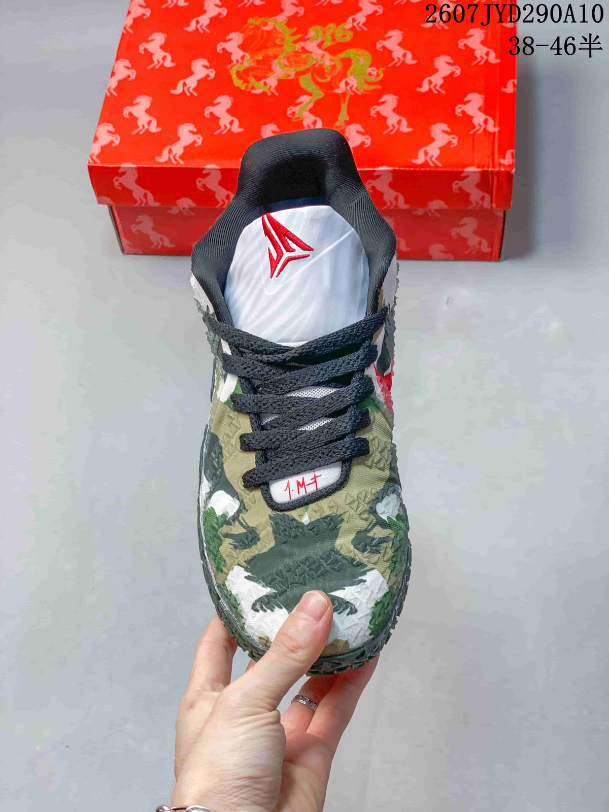 Top view showing black laces, white tongue, red Ja branding, and camouflage-style toe area.