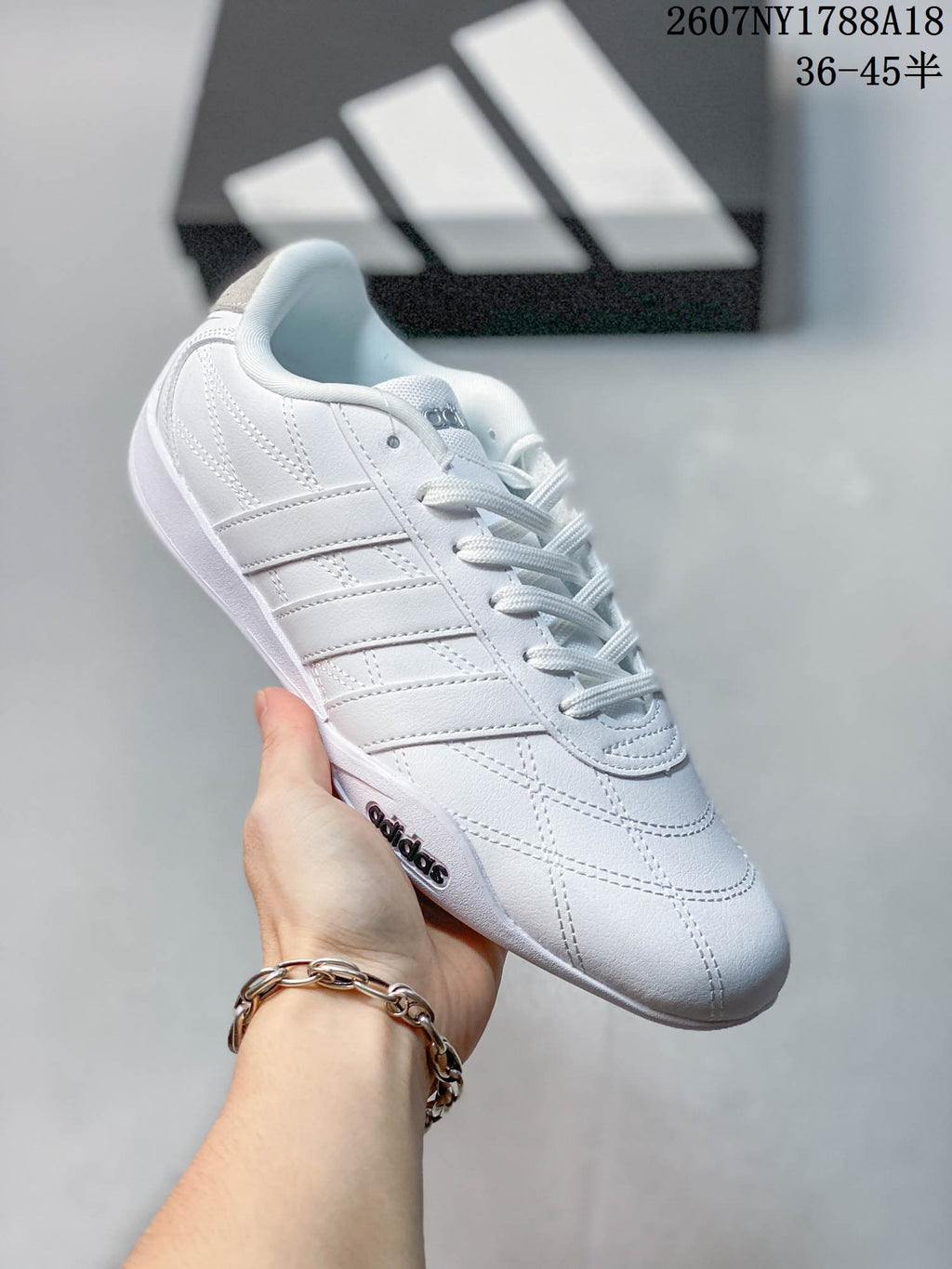 Close side view of a white adidas Adipista trainer with stitched panels and a white outsole.