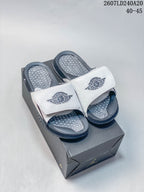 Pair of white and navy Nike Air Jordan slides displayed on a black shoebox; overlay text shows style code 2607LD240A20 and size range 40–45.