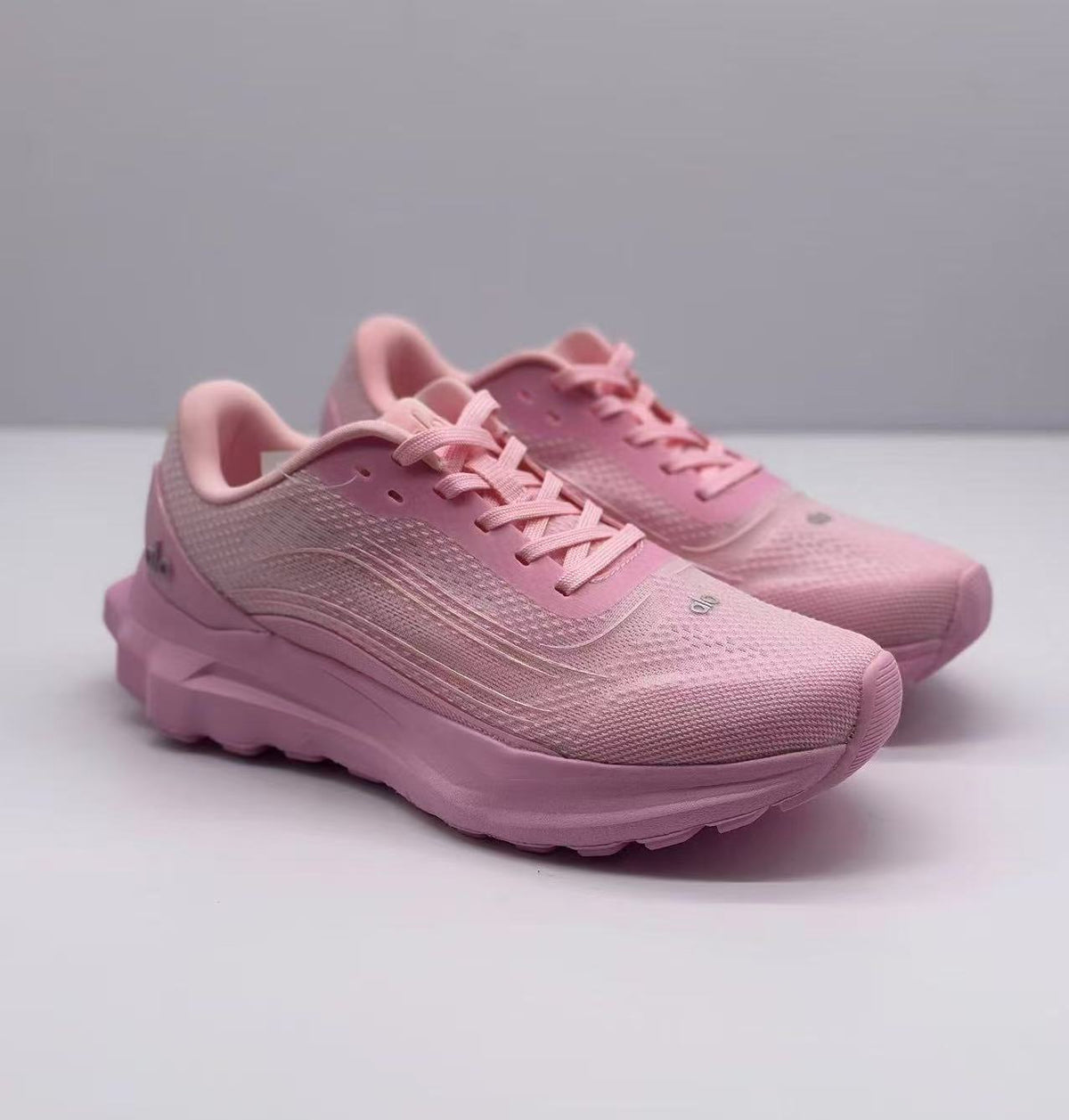 Three-quarter front view of a pair of pink Alo sneakers with lace-up fronts and textured uppers.