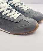 Close-up of the stitched toe panel, gray upper, white laces, and brown outsole edge.