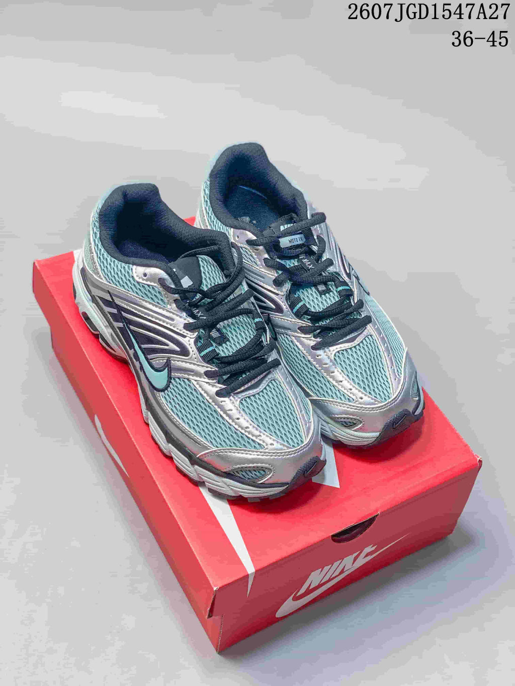 Pair of Nike Air Max Moto 2K sneakers in silver, teal, and black displayed on a red shoebox.