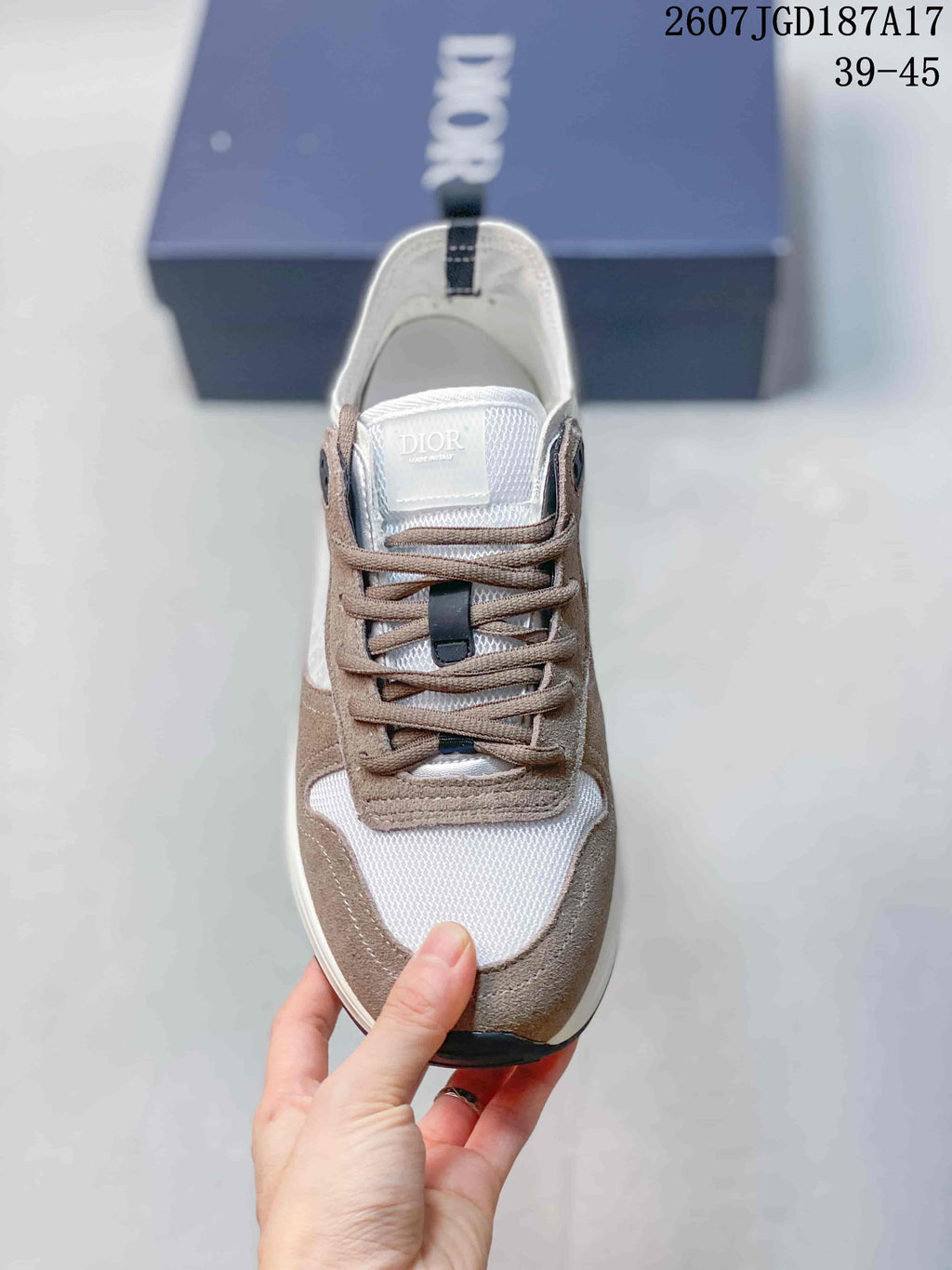 Top view of the sneaker showing the white mesh toe area, taupe overlays, brown laces, and branded tongue.