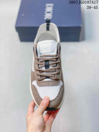 Top view of the sneaker showing the white mesh toe area, taupe overlays, brown laces, and branded tongue.