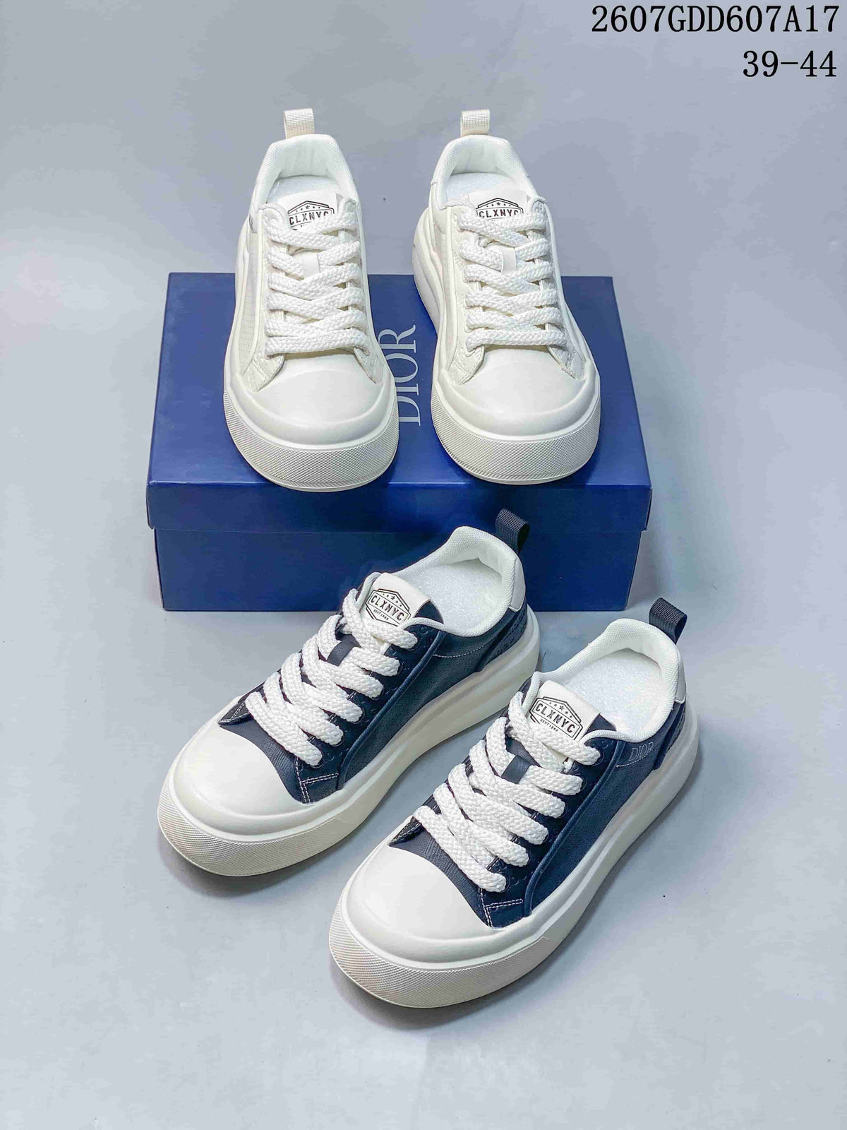 White and navy Dior low-top sneakers arranged around a blue Dior shoe box, showing both colorways and their lace-up construction.